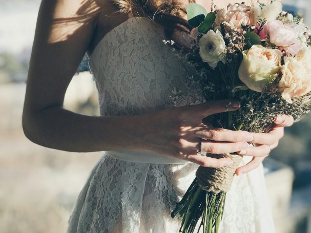 Hochzeit: Frau in weißem Kleid hält einen Blumenstrauß.